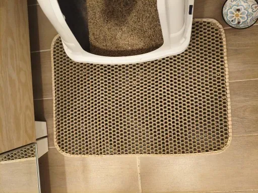 Tapis de litière posé devant une maison de toilette pour chat